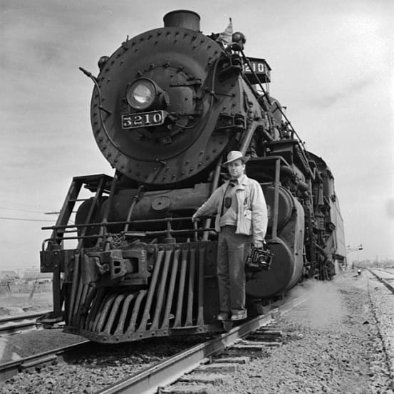 Portrait of photographer Jack Delano and a locomotive