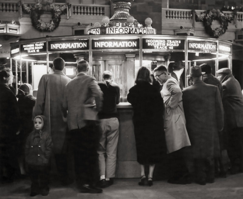 12/1957 - a boy stands alone in front of the Grand Central information booth